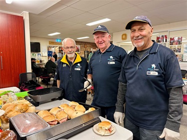 3 men smiling at the camera nearby a breakfast table at the AMSA event