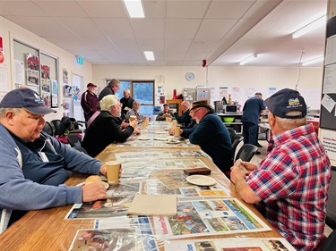 a group of men sitting around a long table chatting at the AMSA event