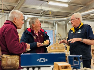 3 men chatting around a woodwork table at the AMSA event