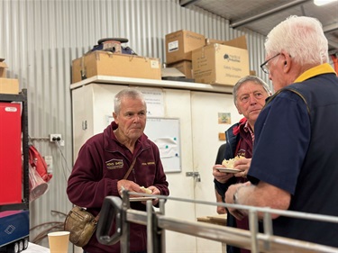 3 men chatting around a woodwork table at the AMSA event