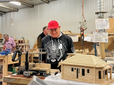 a man wearing a red hat looking at samples of woodwork at the AMSA event