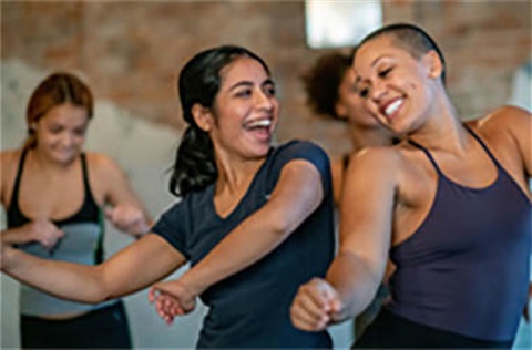 two women smiling and having fun together during a dance class